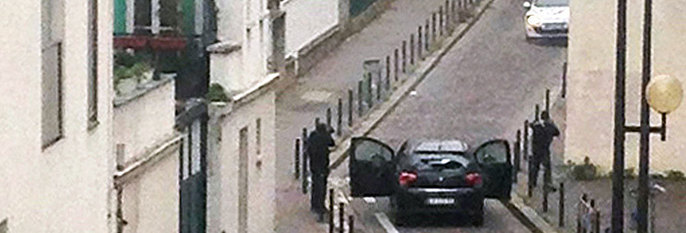  SKYTING:  To personer peker våpnene sine mot politiet i Paris i Frankrike. Terrorister drepte onsdag 12 personer som jobbet i et blad.